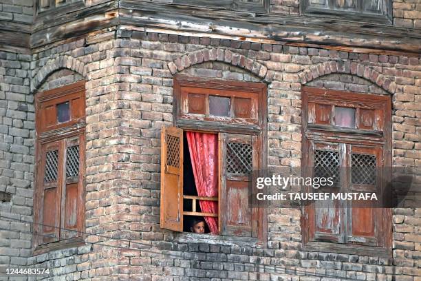Boy looks out from a window of a house as a Muslim cleric displays a relic marking the last friday of 'urs', or death anniversary of the sufi saint...
