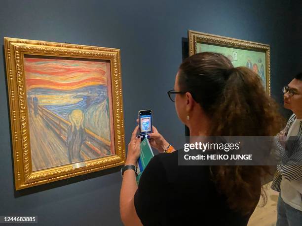 Picture taken on August 3, 2022 shows a visitor taking pictures of Edvard Munch's iconic painting "The Scream" at the National Museum in Oslo,...