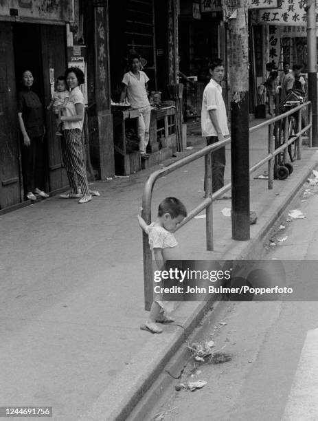 Street scene in Hong Kong with a little boy urinating into the gutter, circa 1963.
