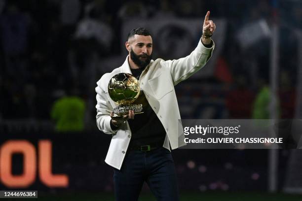 Real Madrid's French forward Karim Benzema poses on the pitch with his Ballon d'Or trophy at half time of the French L1 football match between...
