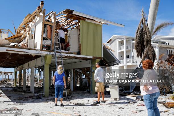Sandy Kulkin climbs a ladder to enter his house for the first time after the passage of Hurricane Ian on September 28 in Fort Myers Beach, Florida,...