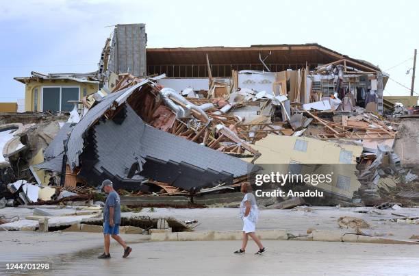 People walk past a home that collapsed onto the beach due to the storm surge and resulting erosion caused by Hurricane Nicole on November 11, 2022 in...