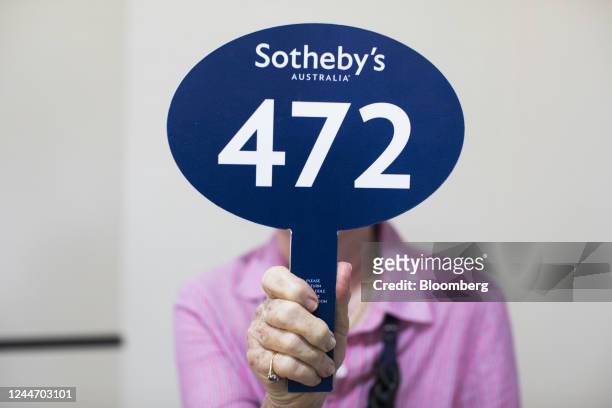 The winner of a residential home auction poses with an auction paddle in the Rose Bay area in Sydney, Australia, on Saturday, Nov. 12, 2022....