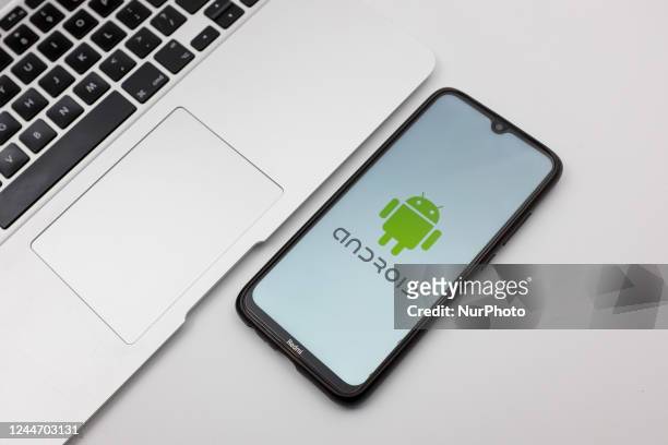 In this photo illustration an Android logo seen displayed on a smartphone screen on a desk next to a Macbook in Athens, Greece on November 12, 2022.