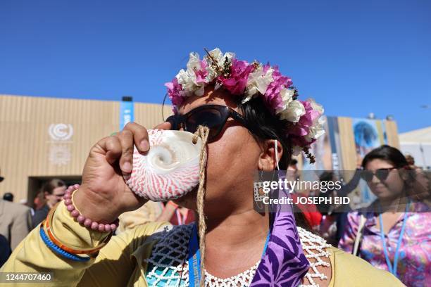 Climate activists blows in a sea shell as she takes part in a protest inside the Sharm el-Sheikh International Convention Centre, during the COP27...