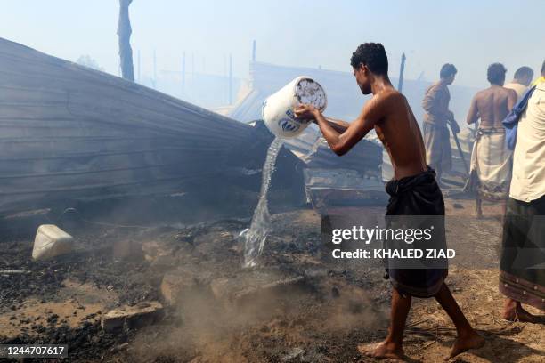 Yemenis put out flames after a fire broke out, burning dozens of huts, in Al-Jishah camp for the internally displaced in al-Khokha district on the...