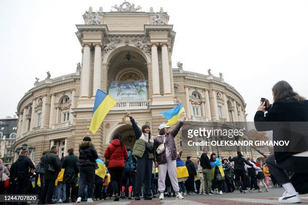 Residents of Kherson temporarily living in Odessa, holding Ukrainian flags, celebrate the liberation of their native town in front of The Odessa...