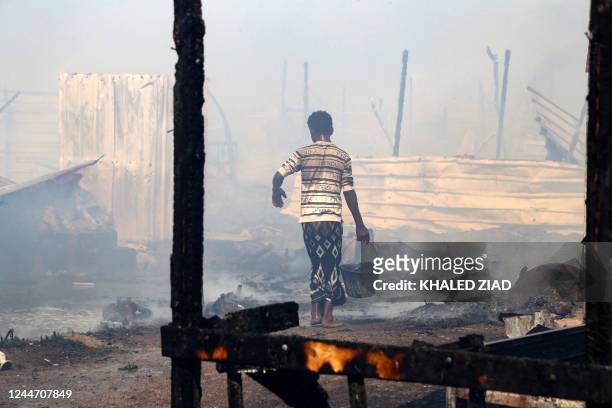 Yemenis put out flames after a fire broke out, burning dozens of huts, in Al-Jishah camp for the internally displaced in al-Khokha district on the...