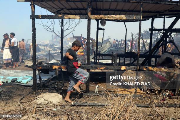 Yemenis put out flames after a fire broke out, burning dozens of huts, in Al-Jishah camp for the internally displaced in al-Khokha district on the...