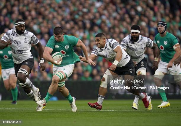 Ireland's Nick Timoney is pulled back by Fiji's Sam Matavesi as he runs with the ball during the Autumn International match at the Aviva Stadium in...