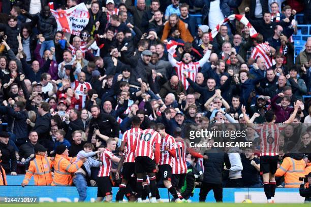 Brentford's English striker Ivan Toney celebrates with teammates in front of their supporters after scoring their late winner during the English...