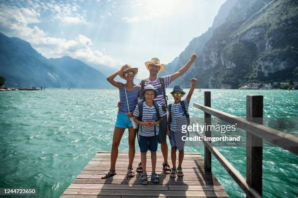 family standing on pier and enjoying view of lake garda - four people stock pictures, royalty-free photos & images