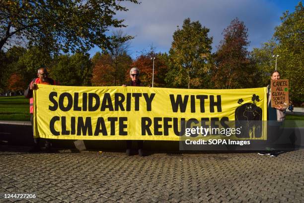 Protesters hold a banner in solidarity with climate refugees during the demonstration outside Shell HQ. Thousands of people gathered outside Shell...