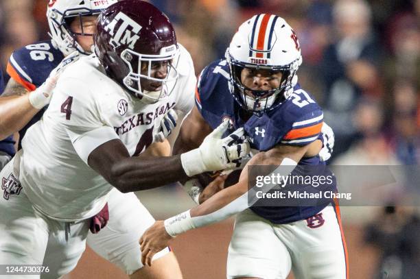 Running back Jarquez Hunter of the Auburn Tigers looks to run the ball by defensive lineman Shemar Stewart of the Texas A&M Aggies during the first...