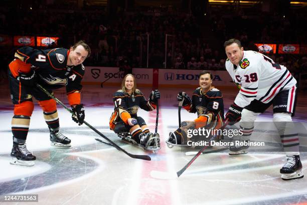 Cam Fowler of the Anaheim Ducks and Jonathan Toews of the Chicago Blackhawks pose for a ceremonial puck drop with Anaheim Ducks Sled Hockey player...