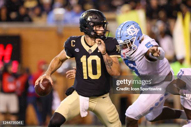 Sam Hartman of the Wake Forest Demon Deacons looks to pass the ball as he is rushed by Jahvaree Ritzie of the North Carolina Tar Heels during a...