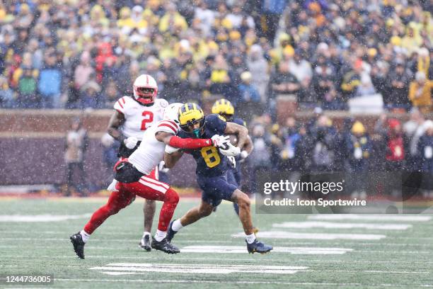 Michigan Wolverines wide receiver Ronnie Bell runs with the ball after catching a pass while trying to avoid being tackled by a Nebraska defender...