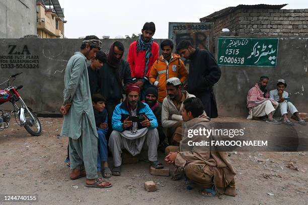 Labourers watch the ICC men's Twenty20 World Cup 2022 final cricket match between Pakistan and England, on a mobile phone along a street in...