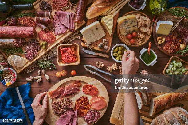 vrouwelijke handen die snacks en voorgerechten in een reeks hoogtepunt van diverse gezouten ham en kaas op rustiek hout voorbereiden - iberische stijl stockfoto's en -beelden