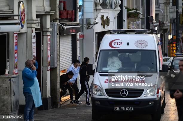 An ambulance rides past people laving a store as Turkish policemen try to secure the area after a strong explosion of unknown origin shook the busy...