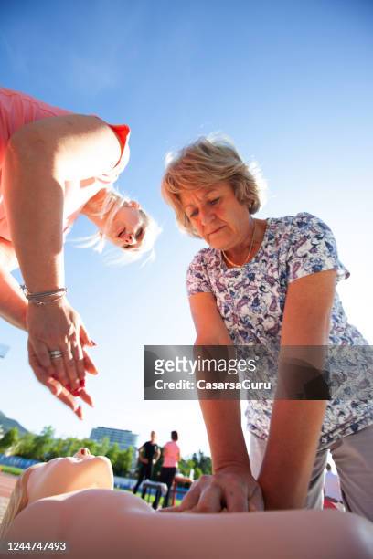 healthcare worker teaching first aid to a senior woman - ems fitness stock pictures, royalty-free photos & images