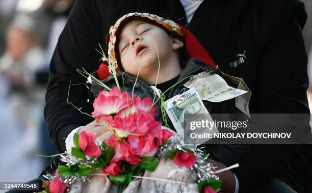 Member of the Muslim community carries his sleepy child during a circumcision ceremony for young boys in the village of Ribnovo, southern Bulgaria on...