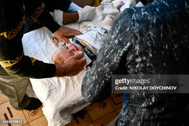 Member of the Muslim community comforts a child while a doctor performs a circumcision during a circumcision ceremony for young boys in the village...