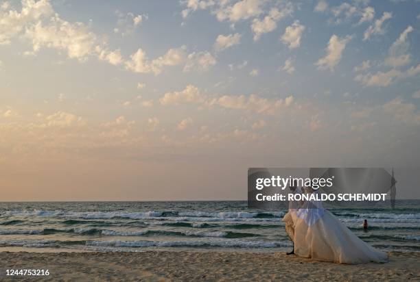 An Arab-Israeli newly-wed couple walk along a beach in the southern coastal city of Ashkelon, near the Gaza Strip, on November 13, 2022