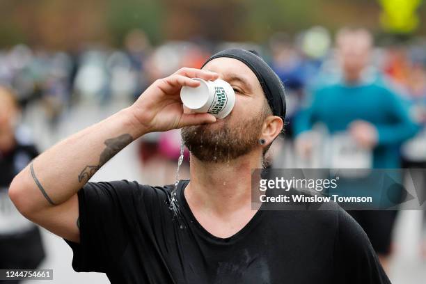 Runner gets a drink as he passes a water station during the Boston Half Marathon on November 13, 2022 in Boston, Massachusetts.