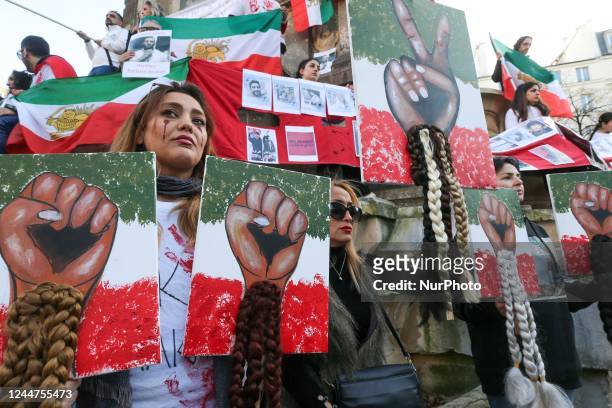 People hold up images and placards during a demonstration in honor of Jina Mahsa Amini and the other protesters killed under the orders of the...