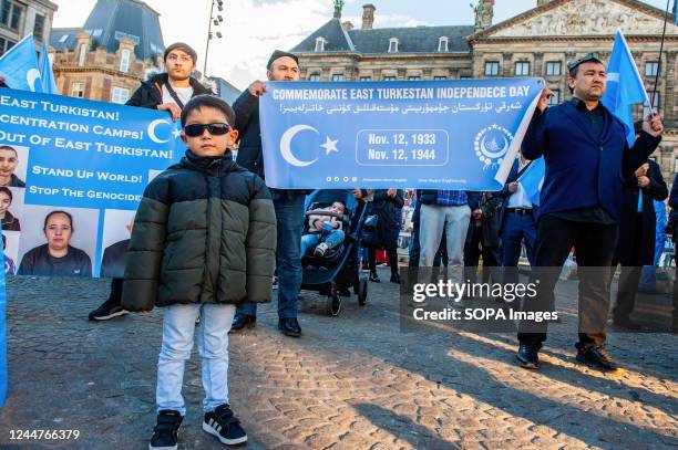 Little Uyghur boy is standing in front of banners in support of the Uyghur people during an event to commemorate the 'National Day of East...