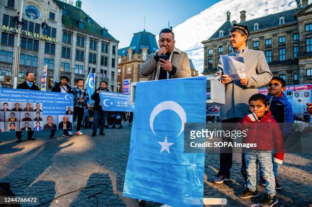 Man speaks about the oppression of the Uyghurs in front of the East Turkestan Kokbayraq flag during an event to commemorate the 'National Day of East...