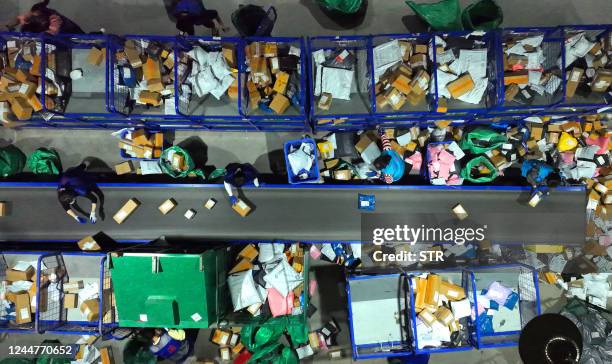 This photo taken on November 12, 2022 shows employees sorting packages for delivery after the Singles Day shopping festival at a logistics center in...