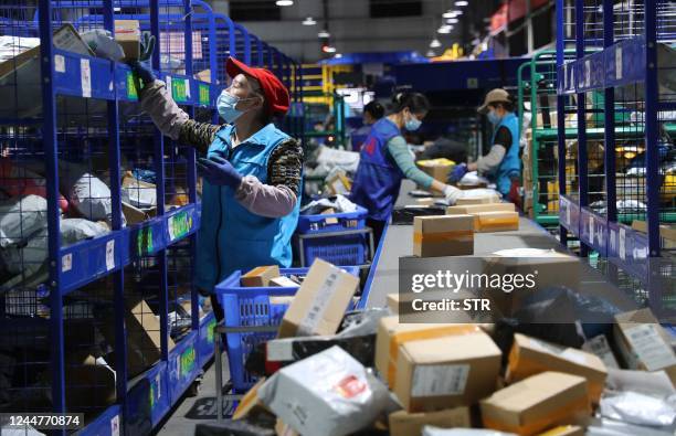 This photo taken on November 12, 2022 shows employees sorting packages for delivery after the Singles Day shopping festival at a logistics center in...