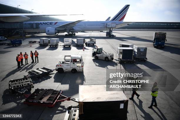 This picture taken on November 10, 2022 shows custom officials monitoring as airfreight is downloaded from a Boeing 777 aircraft docked at its...