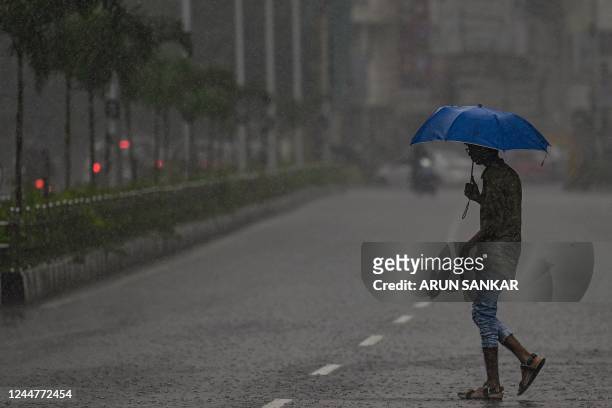 Pedestrian holds an umbrella as he walks along a road during a heavy monsoon rainfall in Chennai on November 14, 2022.