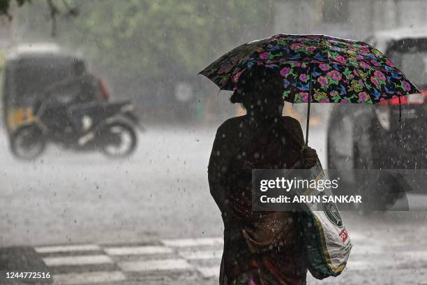 Woman holds an umbrella as she walks along a road during a heavy monsoon rainfall in Chennai on November 14, 2022.