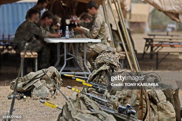 Weapons fitted with laser-guided targeting systems sit propped against tactical backpacks next to a mess where soldiers that are part of a training...