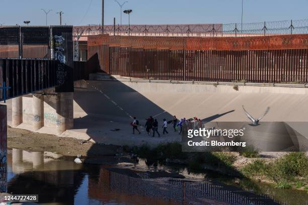 Migrants walk near the US and Mexico border wall in El Paso, Texas, after crossing from Ciudad Juarez, Mexico, on Sunday, Nov. 13, 2022. Poverty in...