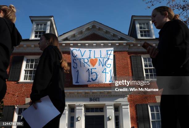 Students walk past a fraternity house with a banner memorializing three University of Virginia football players killed during an overnight shooting...