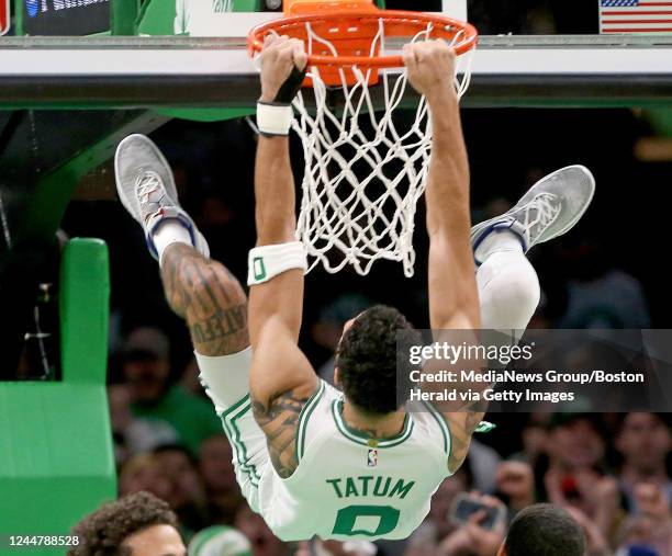 November 14: Jayson Tatum of the Boston Celtics hangs from the basket after dunking during the second half of the NBA game against the Oklahoma City...