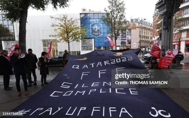 French Young Communists Movement members unfold a jersey as they demonstrate in front of the French Football Federation headquarters to denounce the...