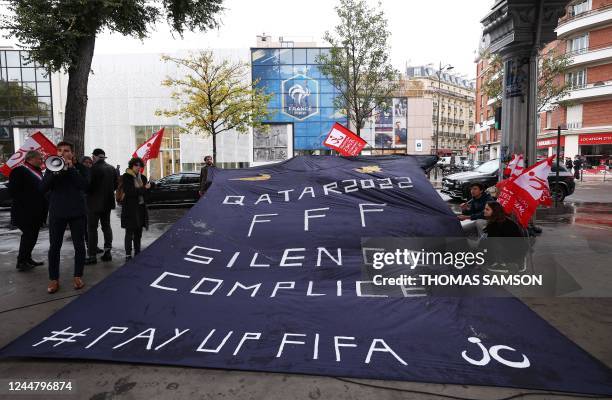 French Young Communists Movement members unfold a jersey as they demonstrate in front of the French Football Federation headquarters to denounce the...