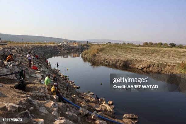 Syrians gather dying fish in the polluted waters of the the Orontes river in Syria's rebel-held Idlib province, near the border with Turkey, on...