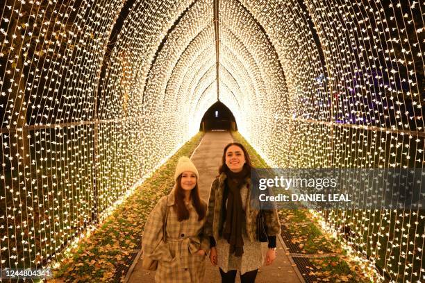 Models pose under light installation during a photocall to preview "Christmas at Kew" at Kew Gardens in southwest London on November 15, 2022. - -