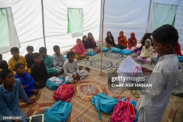 In this picture taken on October 28 a boy reads a book at a makeshift tent school in the flooded area of Chandan Mori, in Dadu district of Sindh...