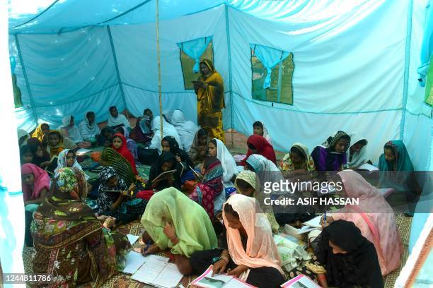 In this picture taken on October 28 a teacher gives lesson at a makeshift tent school in the flood-affected Mounder town, in Dadu district of Sindh...