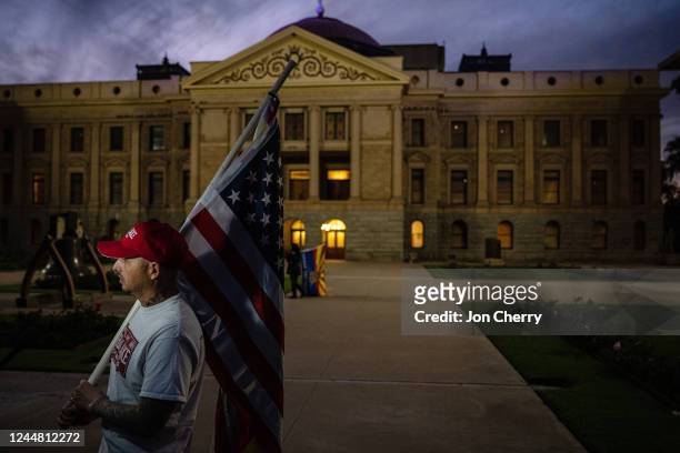 Supporter of Republican gubernatorial nominee Kari Lake is illuminated by a television camera while he stands in protest at the Arizona State Capitol...