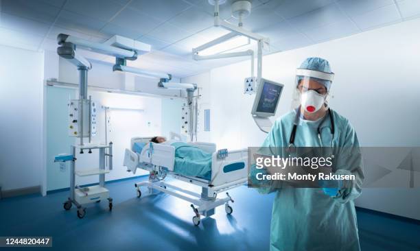 doctor wearing protective gear in icu during the covid-19 global pandemic. - coronavirus patient stock pictures, royalty-free photos & images