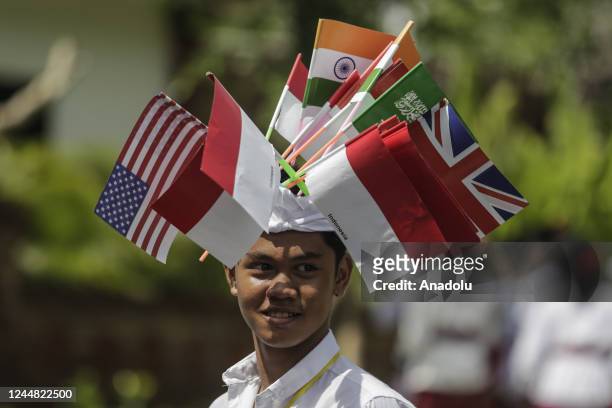 Balinese kid is seen with flags as they wait for head of state's vehicles passes to Tahura Mangrove Forest within G20 Leaders' Summit in Nusa Dua,...